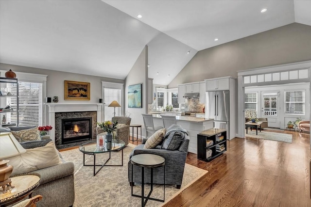 living room featuring high vaulted ceiling, a wealth of natural light, a fireplace, and light hardwood / wood-style flooring