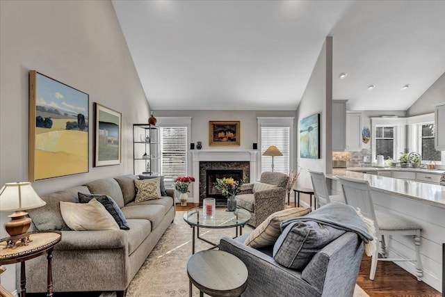 living room featuring a premium fireplace, lofted ceiling, and light hardwood / wood-style floors