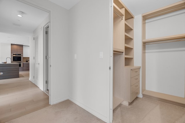 walk in closet featuring light hardwood / wood-style flooring and sink