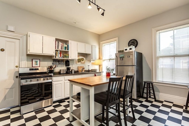 36 7th St, New Bedford, MA 02740 - kitchen with appliances with stainless steel finishes, light floors, butcher block counters, open shelves, and white cabinets
