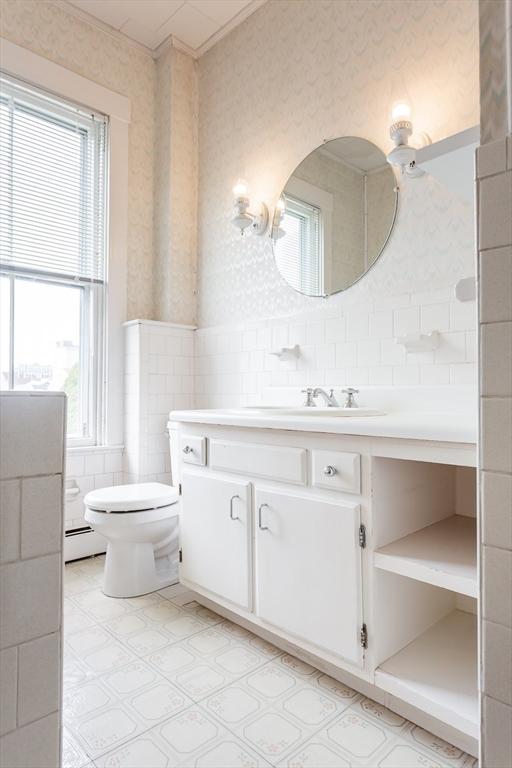 36 7th St, New Bedford, MA 02740 - bathroom featuring wallpapered walls, tile walls, vanity, baseboard heating, and toilet