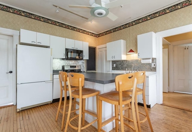 36 7th St, New Bedford, MA 02740 - kitchen with freestanding refrigerator, black microwave, stove, light wood-style flooring, and wallpapered walls
