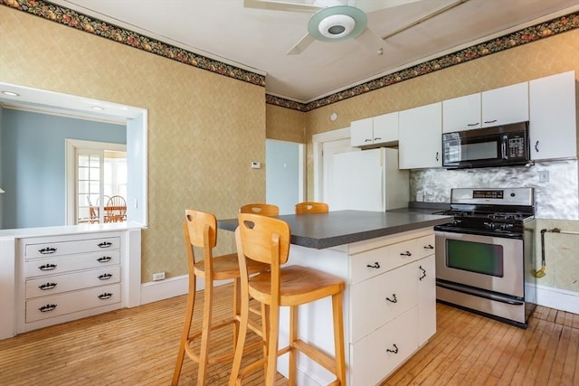 36 7th St, New Bedford, MA 02740 - kitchen featuring black microwave, gas range, freestanding refrigerator, light wood-style flooring, and a ceiling fan