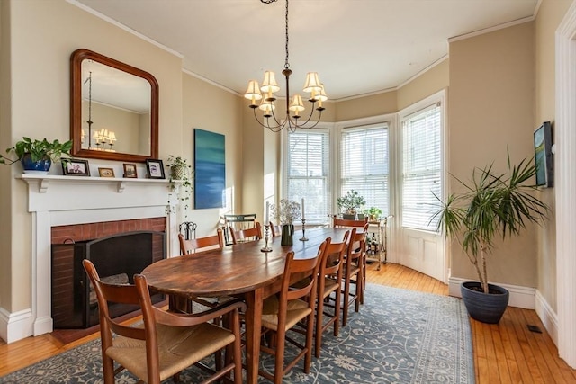 36 7th St, New Bedford, MA 02740 - dining space featuring a chandelier, light wood-style flooring, a fireplace, and crown molding