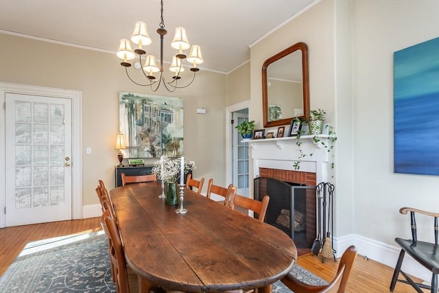 36 7th St, New Bedford, MA 02740 - dining space with a chandelier, light wood-style flooring, ornamental molding, a fireplace, and baseboards