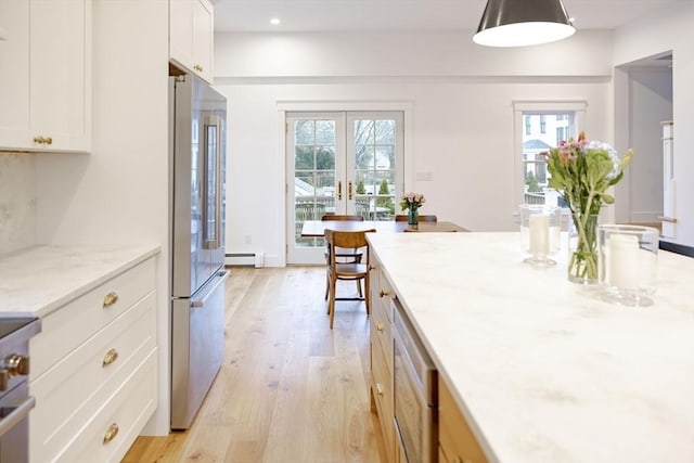 kitchen featuring high quality fridge, pendant lighting, white cabinetry, a baseboard heating unit, and light stone counters