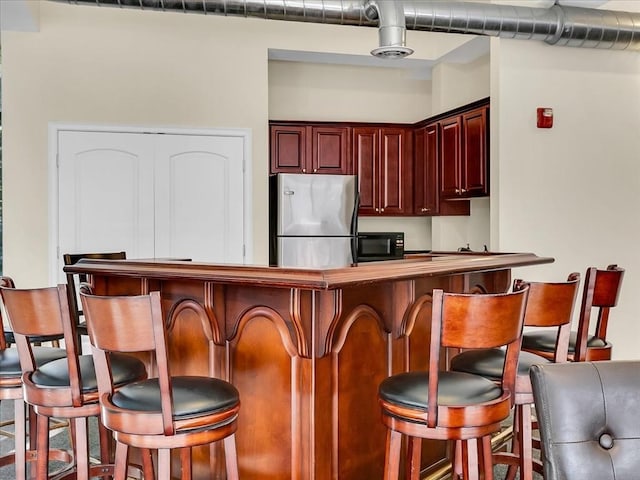 kitchen featuring stainless steel fridge and a kitchen breakfast bar