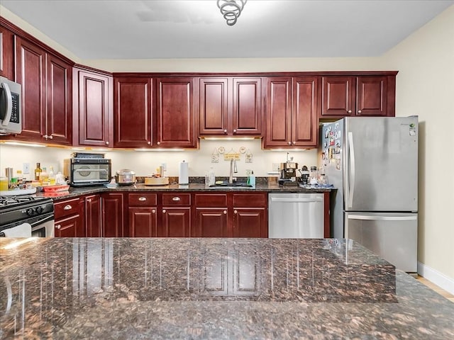 kitchen featuring stainless steel appliances, sink, and dark stone counters