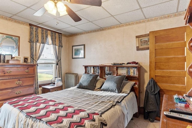 carpeted bedroom featuring a drop ceiling and a ceiling fan