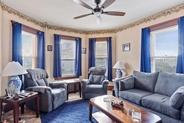 living area with ceiling fan and dark carpet