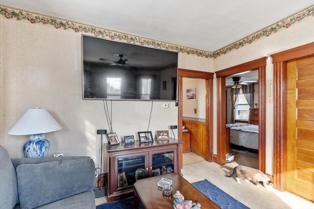 carpeted living area with wainscoting, a ceiling fan, and wooden walls