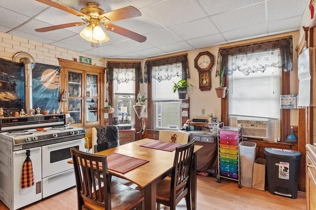 dining space with cooling unit, a paneled ceiling, light wood finished floors, and ceiling fan