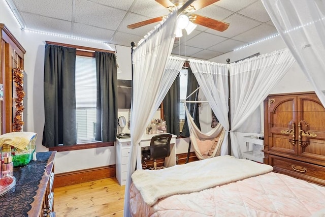 bedroom featuring a paneled ceiling, hardwood / wood-style flooring, baseboards, and ceiling fan