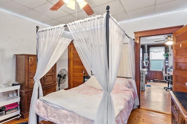 bedroom with a paneled ceiling and wood finished floors