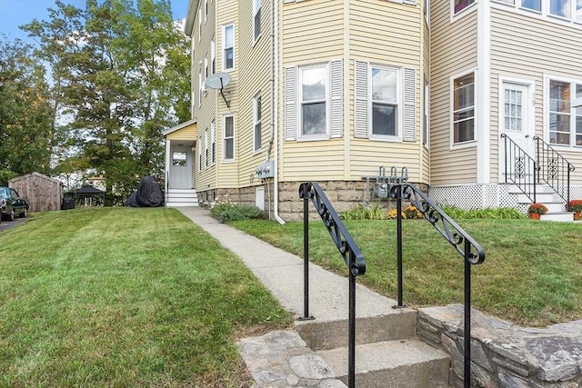 view of side of home with entry steps and a lawn