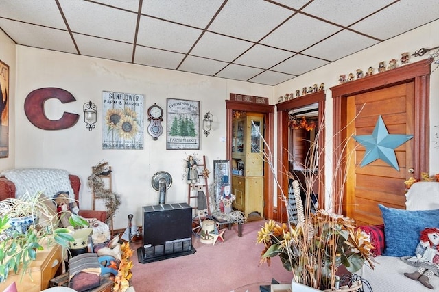 carpeted living area with a drop ceiling
