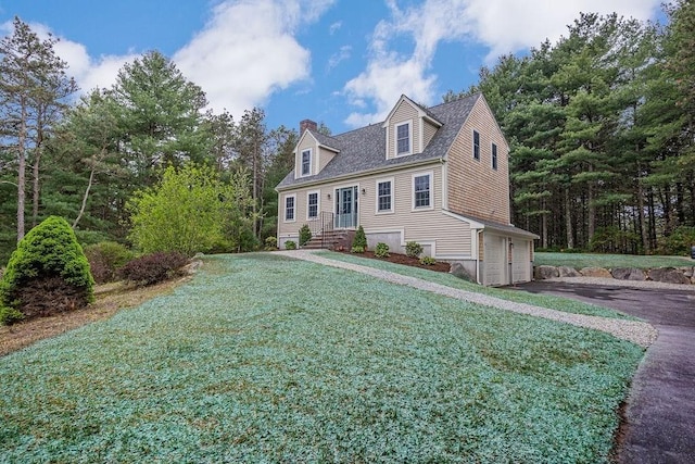 new england style home with a chimney, driveway, a garage, and a front lawn