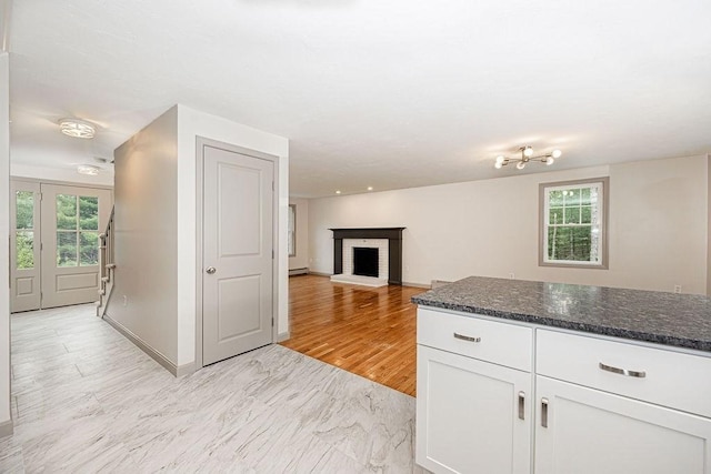kitchen with healthy amount of natural light, white cabinets, dark stone countertops, and a fireplace