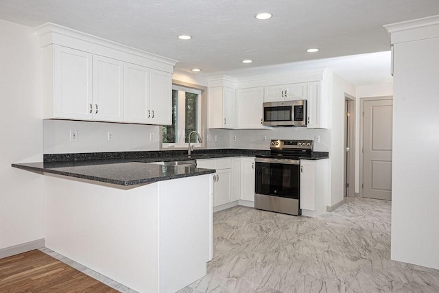 kitchen featuring stainless steel appliances, white cabinets, a peninsula, dark stone counters, and recessed lighting