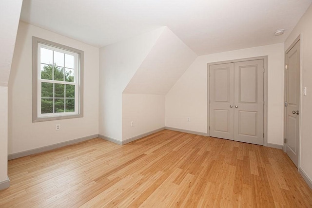 bonus room featuring light wood-style flooring, baseboards, and lofted ceiling