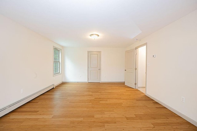 empty room with a baseboard heating unit, light wood-style floors, and baseboards