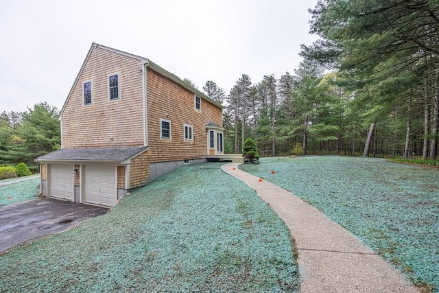 view of home's exterior with asphalt driveway, a garage, and a yard
