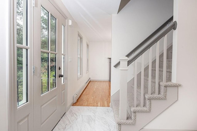 foyer entrance with baseboard heating and stairs