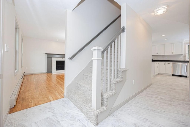 stairs featuring a baseboard radiator, a fireplace, recessed lighting, marble finish flooring, and baseboards