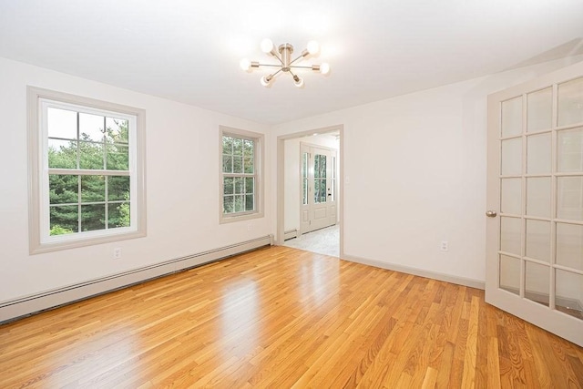 empty room featuring a baseboard radiator, a chandelier, wood finished floors, and baseboards