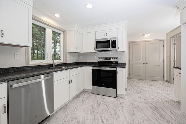 kitchen with appliances with stainless steel finishes, a sink, white cabinets, light marble finish flooring, and recessed lighting