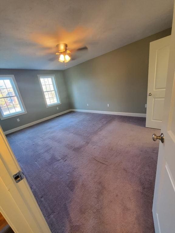 unfurnished room with dark colored carpet and ceiling fan