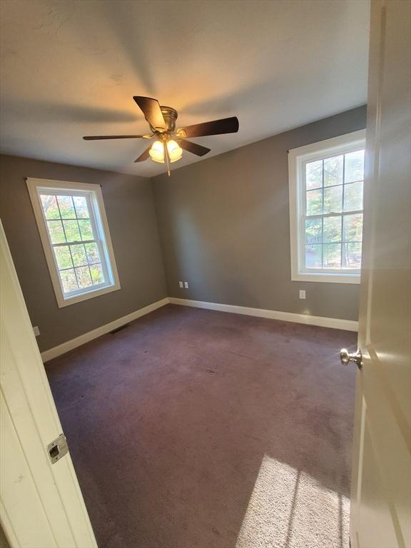 unfurnished room with dark colored carpet and ceiling fan