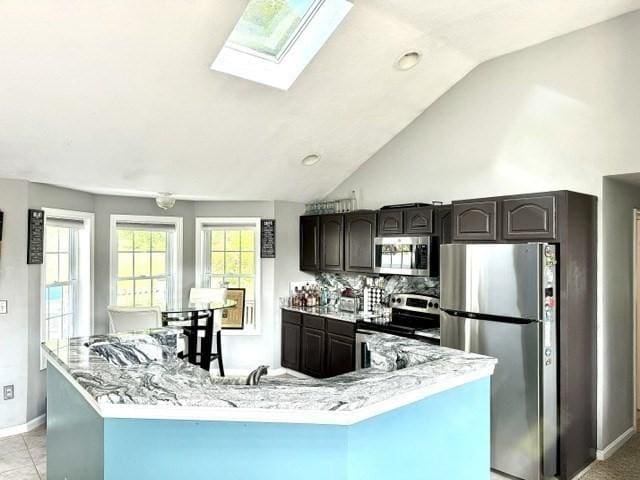 62 Moreland Green Dr, Worcester, MA 01609 - kitchen featuring stainless steel appliances, a skylight, baseboards, vaulted ceiling, and a center island with sink