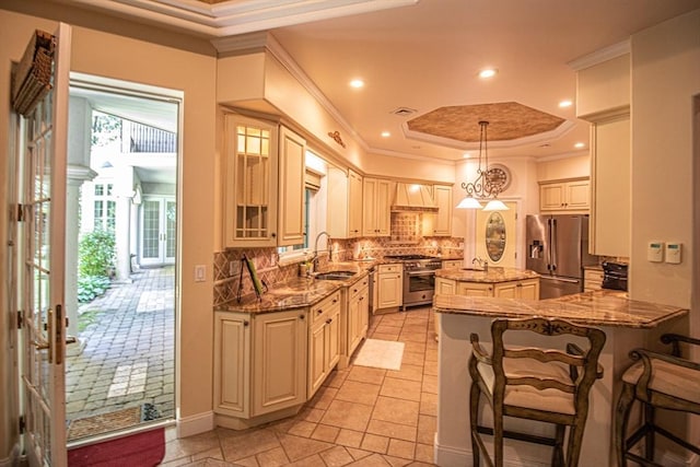 kitchen with hanging light fixtures, high end appliances, a kitchen island, a raised ceiling, and dark stone counters