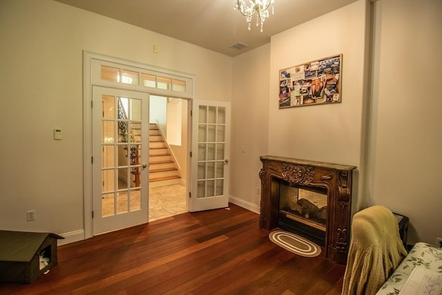 doorway to outside with a multi sided fireplace, dark wood-type flooring, a notable chandelier, and french doors