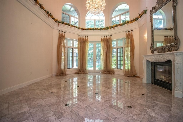 interior space with a premium fireplace, a towering ceiling, and a notable chandelier