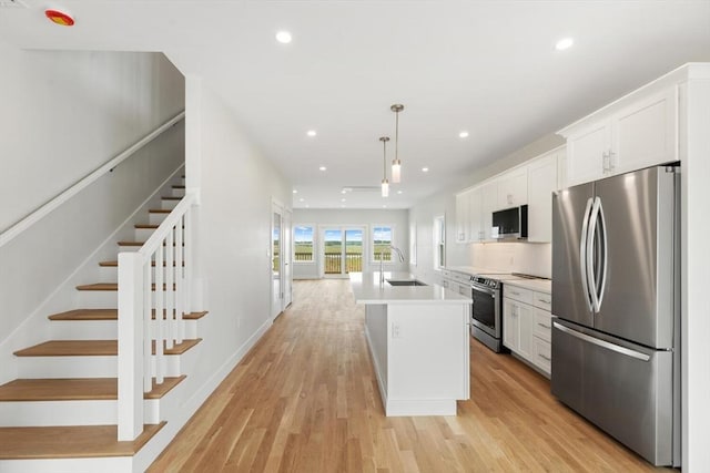 77 N End Blvd Unit 2, Salisbury, MA 01952 - kitchen with appliances with stainless steel finishes, a sink, white cabinets, a center island with sink, and light wood-style floors