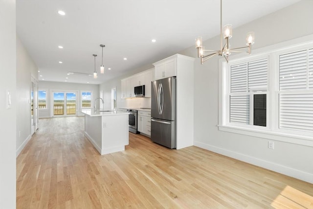 77 N End Blvd Unit 2, Salisbury, MA 01952 - kitchen featuring stainless steel appliances, a chandelier, white cabinets, a center island with sink, and light countertops