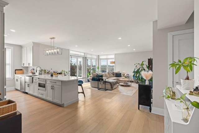 kitchen featuring a breakfast bar area, a peninsula, light countertops, light wood-type flooring, and a sink