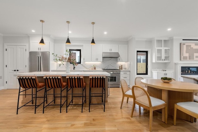 832 E 3rd Unit A, Boston, MA 02127 - kitchen with appliances with stainless steel finishes, under cabinet range hood, a center island, crown molding, and white cabinets