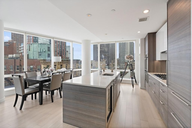 1 Franklin St Unit 1504, Boston, MA 02110 - kitchen with modern cabinets, a sink, appliances with stainless steel finishes, an island with sink, and light wood finished floors