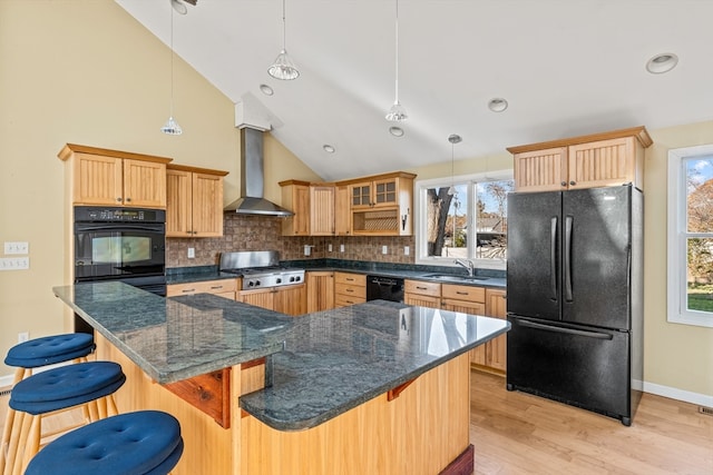 kitchen with black appliances, pendant lighting, wall chimney exhaust hood, and a kitchen breakfast bar