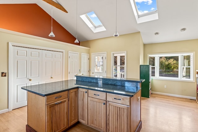 kitchen with dark stone counters, high vaulted ceiling, pendant lighting, light hardwood / wood-style floors, and a center island