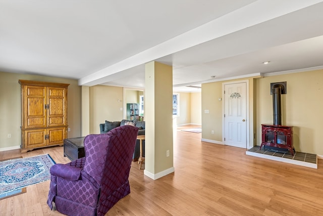 living room featuring light wood-type flooring, a wood stove, and ornamental molding