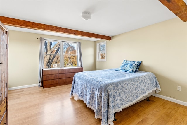 bedroom with light hardwood / wood-style floors and beam ceiling