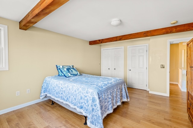 bedroom with hardwood / wood-style floors and beam ceiling