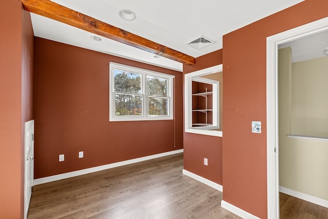 unfurnished room featuring hardwood / wood-style floors and beam ceiling