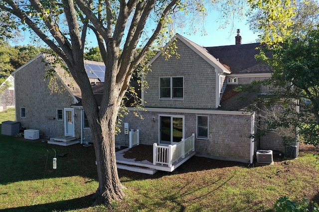 back of property with central AC and a lawn