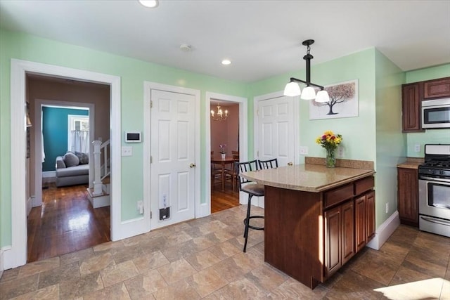 kitchen featuring appliances with stainless steel finishes, hanging light fixtures, a kitchen bar, kitchen peninsula, and a chandelier