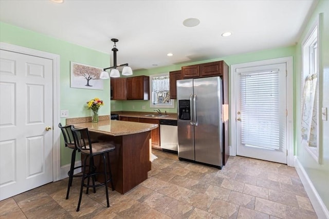 kitchen featuring sink, stainless steel appliances, a kitchen bar, decorative light fixtures, and kitchen peninsula